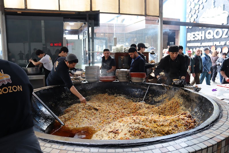 Cooks stirring an enormous plov cauldron at Besh Qozon restaurant in Tashkent, Uzbekistan