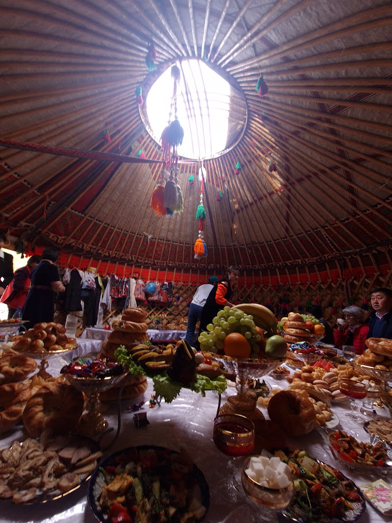 Traditional Kyrgyz yurt interior with Nowruz feast spread beneath the tunduk skylight
