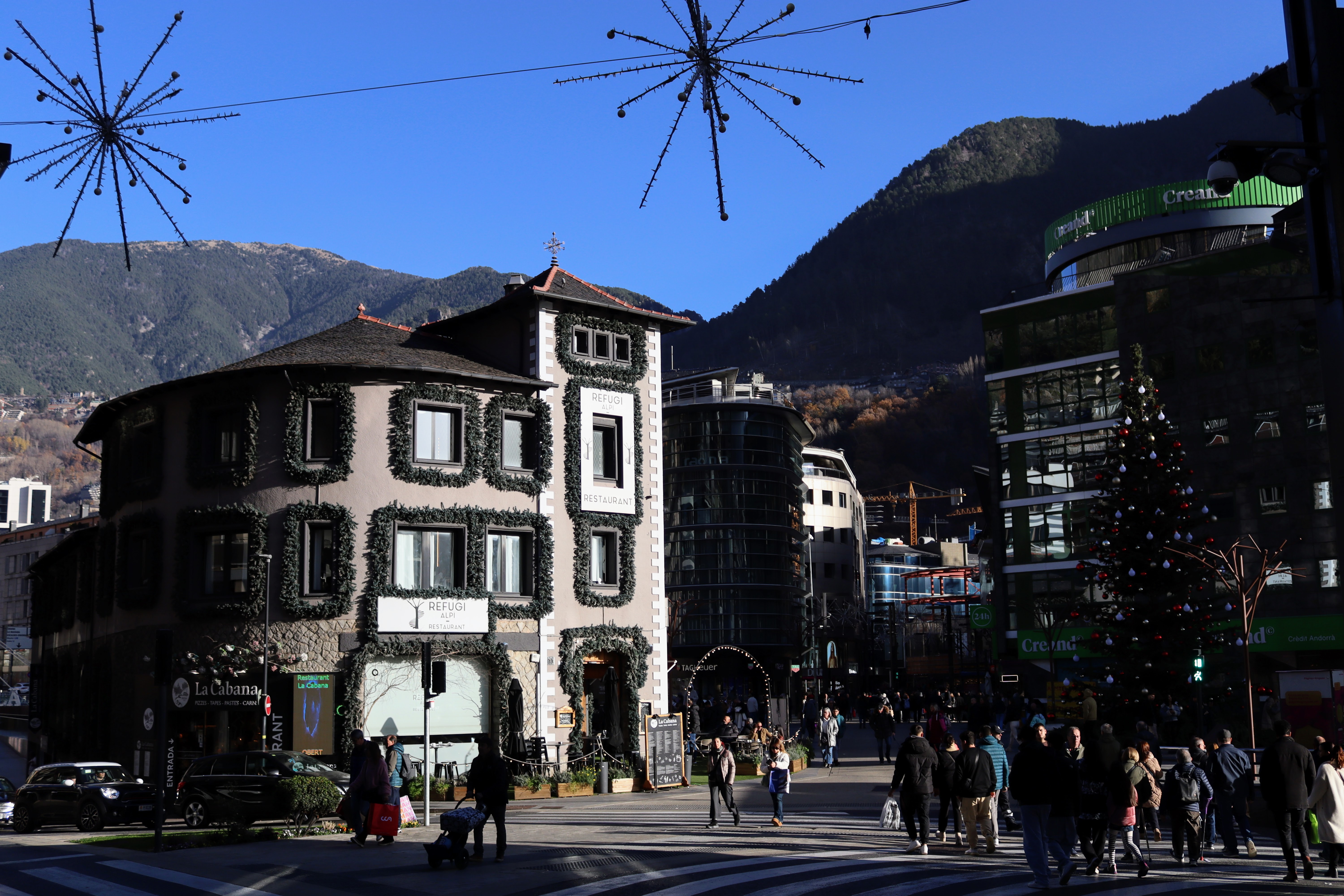 Christmas-decorated town square in Andorra la Vella with ivy-covered buildings and snow-dusted mountains behind