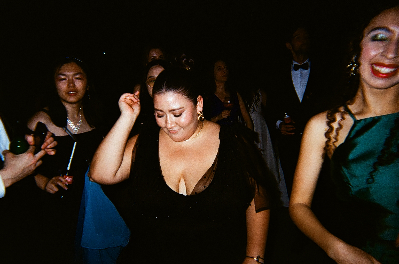 Film-grain shot of guests dancing in formal wear at a dark venue in Almaty
