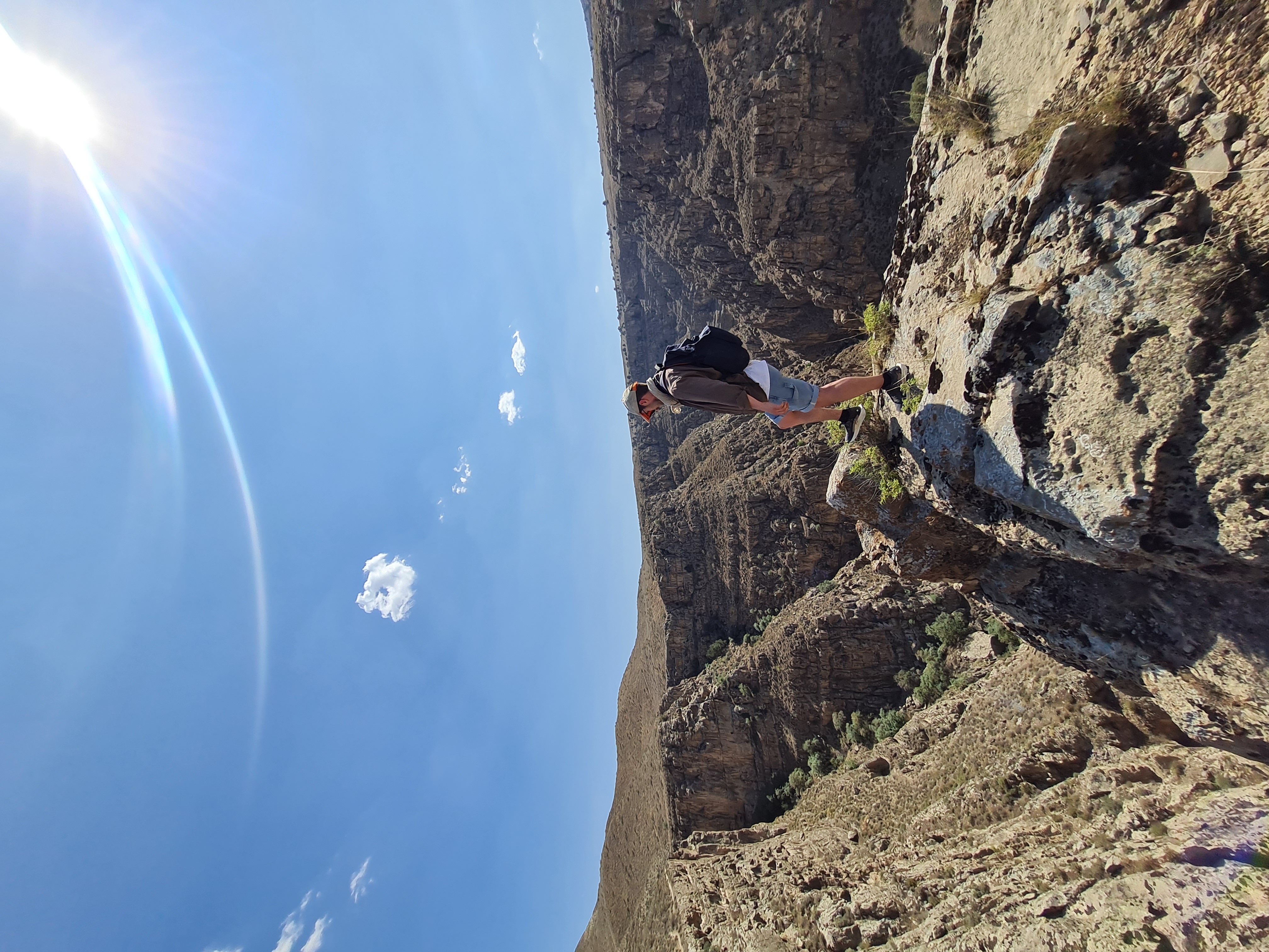 Hiker standing on the lip of a dramatic rocky canyon in Chuli Gorge under a vivid blue sky near Ashgabat