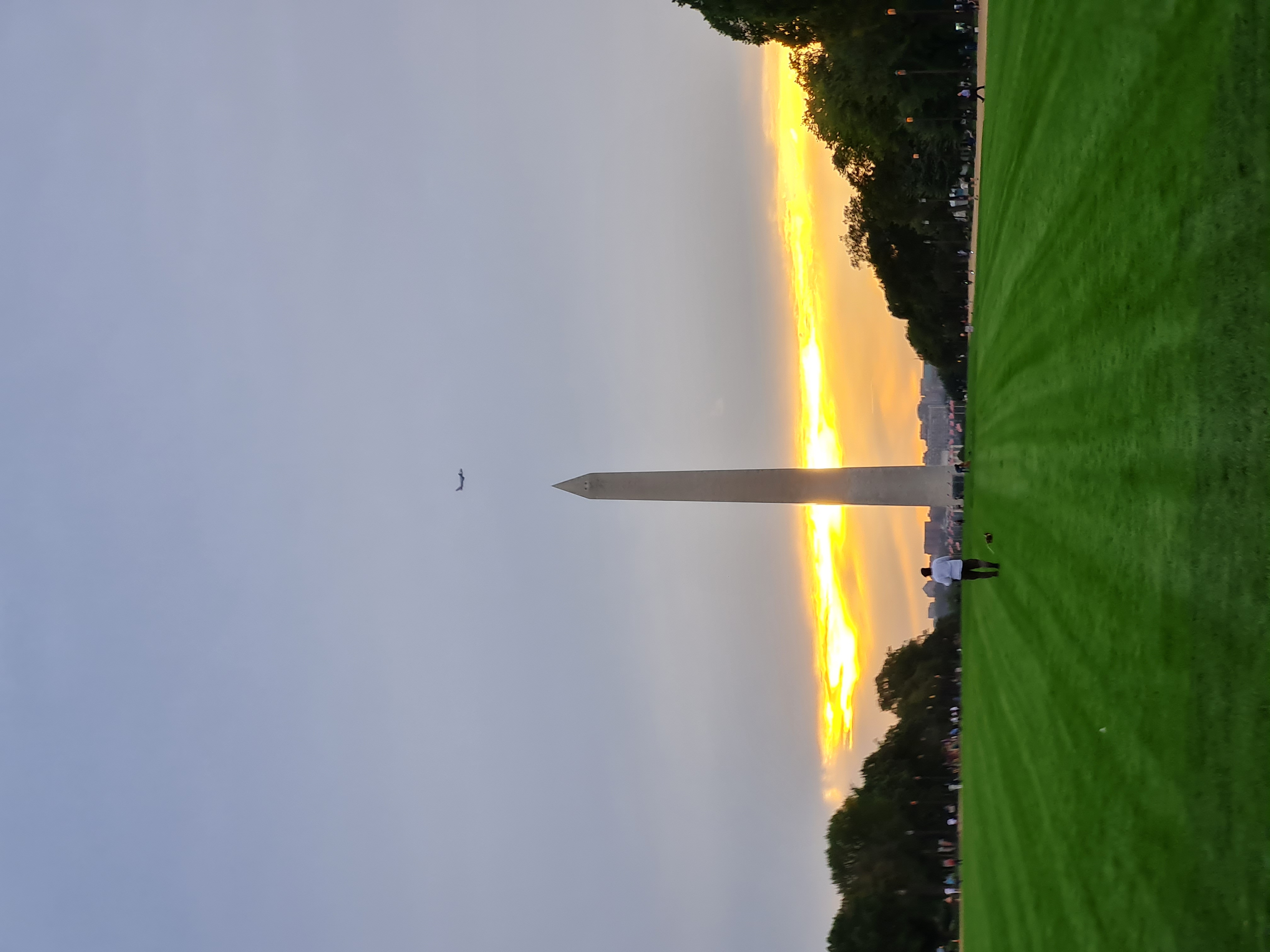 Washington Monument silhouetted against a blazing golden sunset sky viewed from the National Mall