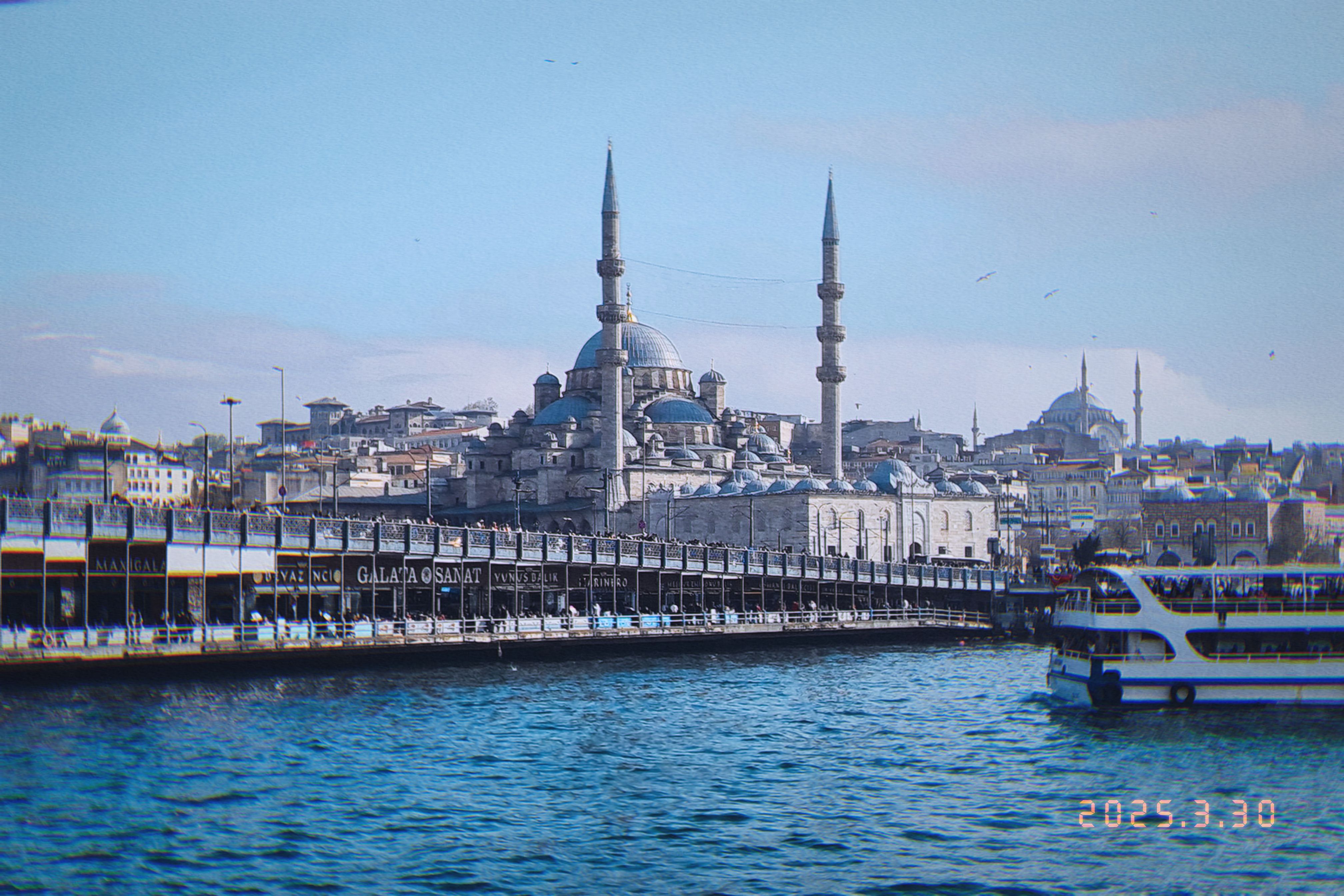 Yeni Cami and its minarets rising above the Galata Bridge over the Golden Horn on a clear Istanbul afternoon